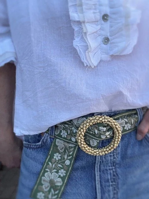 Soft green floral belt laid flat showing cream embroidered flowers