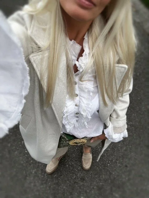 White ruffle blouse layered under a light neutral blazer.