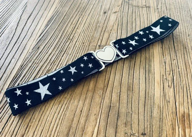 Close-up detail of silver heart clasp and star charm accents on women's belt