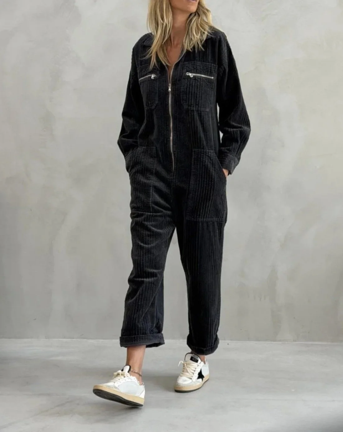 Full-length view of black Banditas Hana Jumpsuit styled with white sneakers