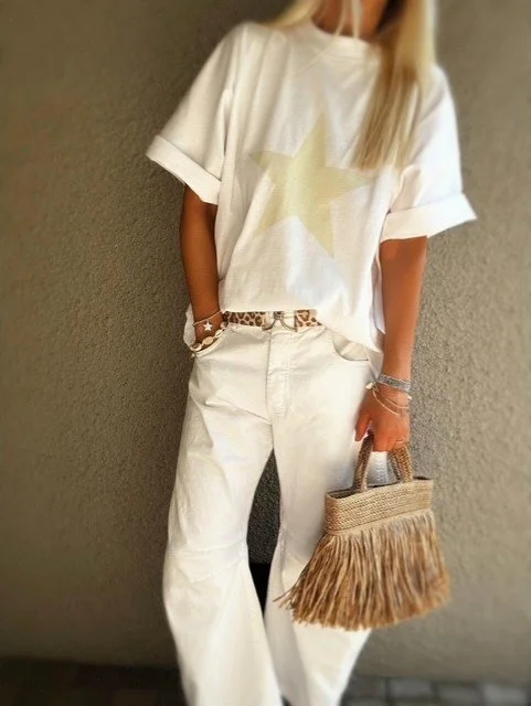 Women’s white barrel leg jeans with white tee and woven fringe bag
