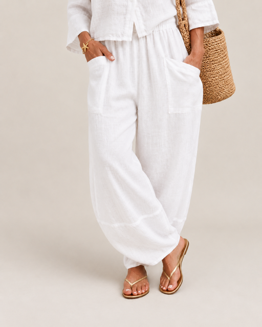 Paia Linen Jogger in White styled with gold sandals and a straw bag