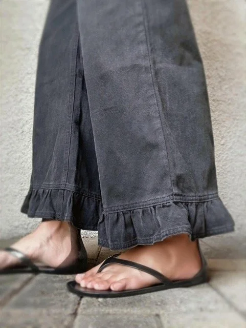 Black frill hem jeans styled with a linen blouse for a coastal look