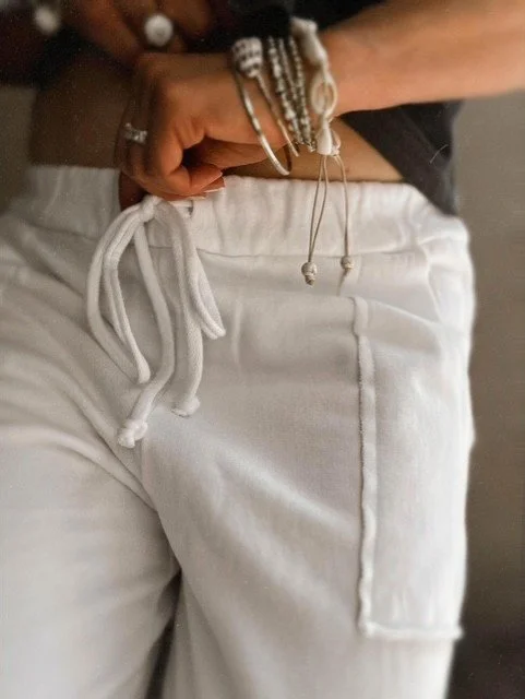 Women's white joggers styled with a casual coastal outfit and sneakers