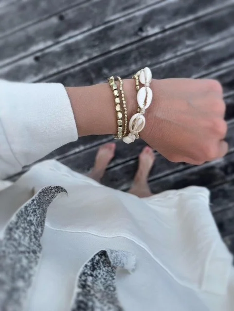 Coastal inspired women's bracelets featuring cowrie shells and gold accents