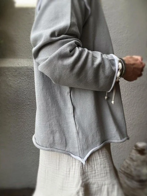 Wren Long Sleeve Knit in grey worn open and layered over a cream gauze blouse with ruffle skirt.