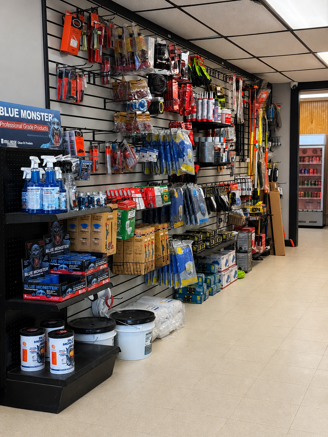 A store aisle with various car care products and tools displayed on black pegboard walls and shelves, including spray bottles, gloves, and containers.