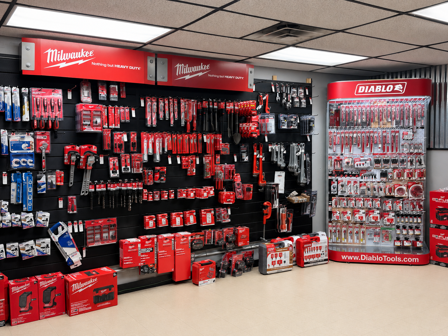 Display of Milwaukee and Diablo brand hand tools and accessories in a hardware store, with a black pegboard wall holding various tools on the left and a white curved display case on the right.