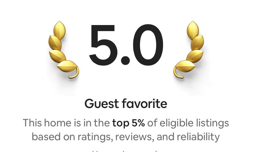 A digital badge indicating a 5.0 guest ratings score with gold laurel leaves on either side, signifying the home is in the top 5% of eligible listings based on ratings, reviews, and reliability.