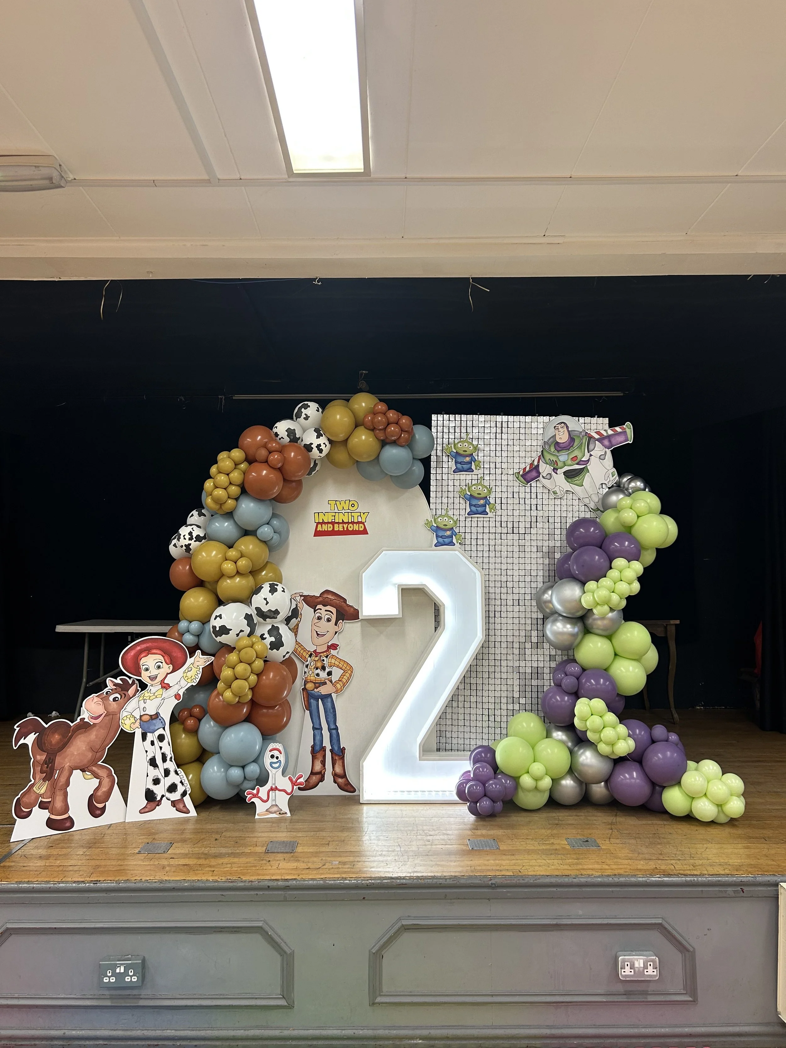 Decorated birthday cake table with balloons, Toy Story characters, and a large number two for a Toy Story themed birthday party.