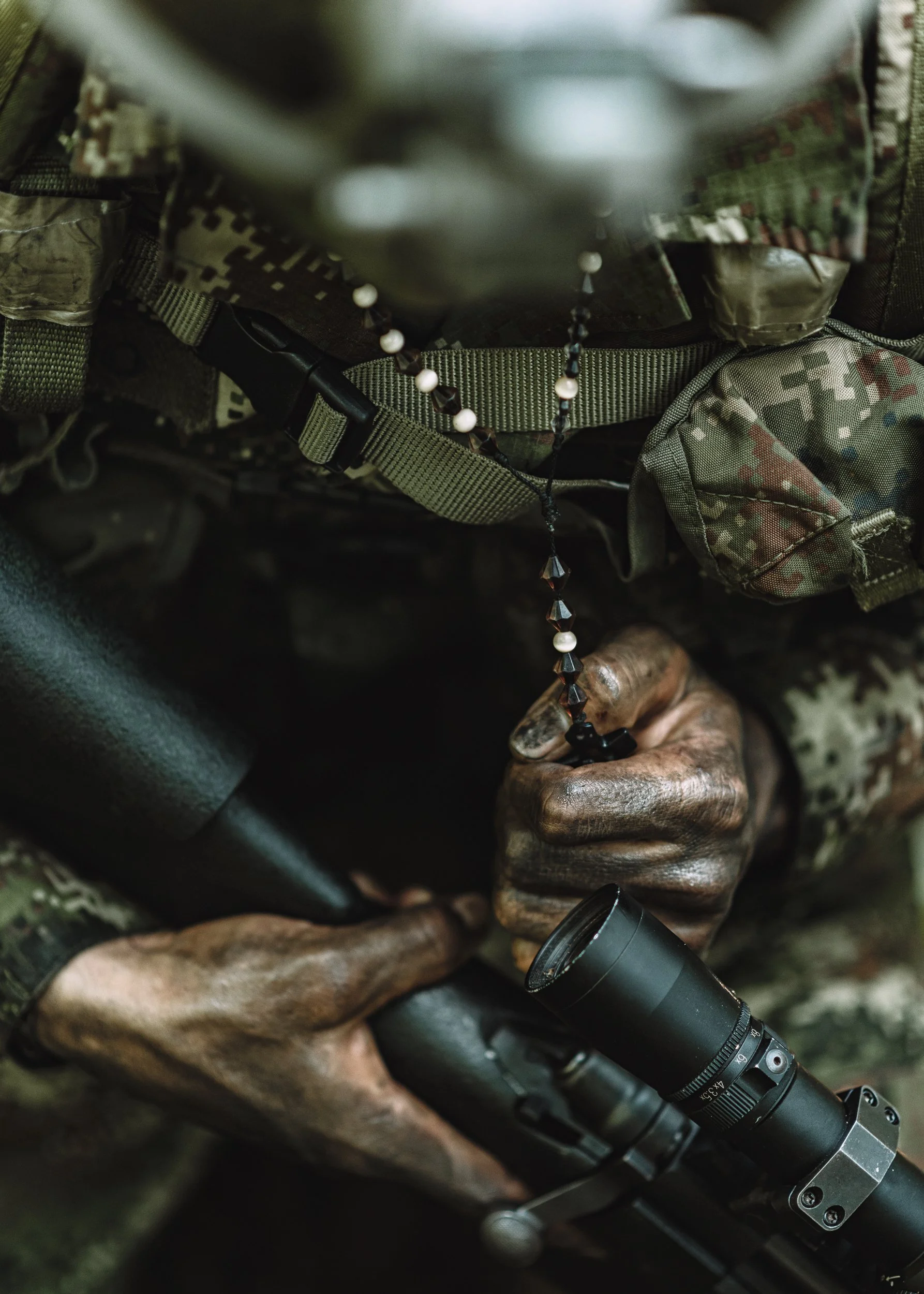 Close-up of a soldier's gloved hand on a scoped rifle