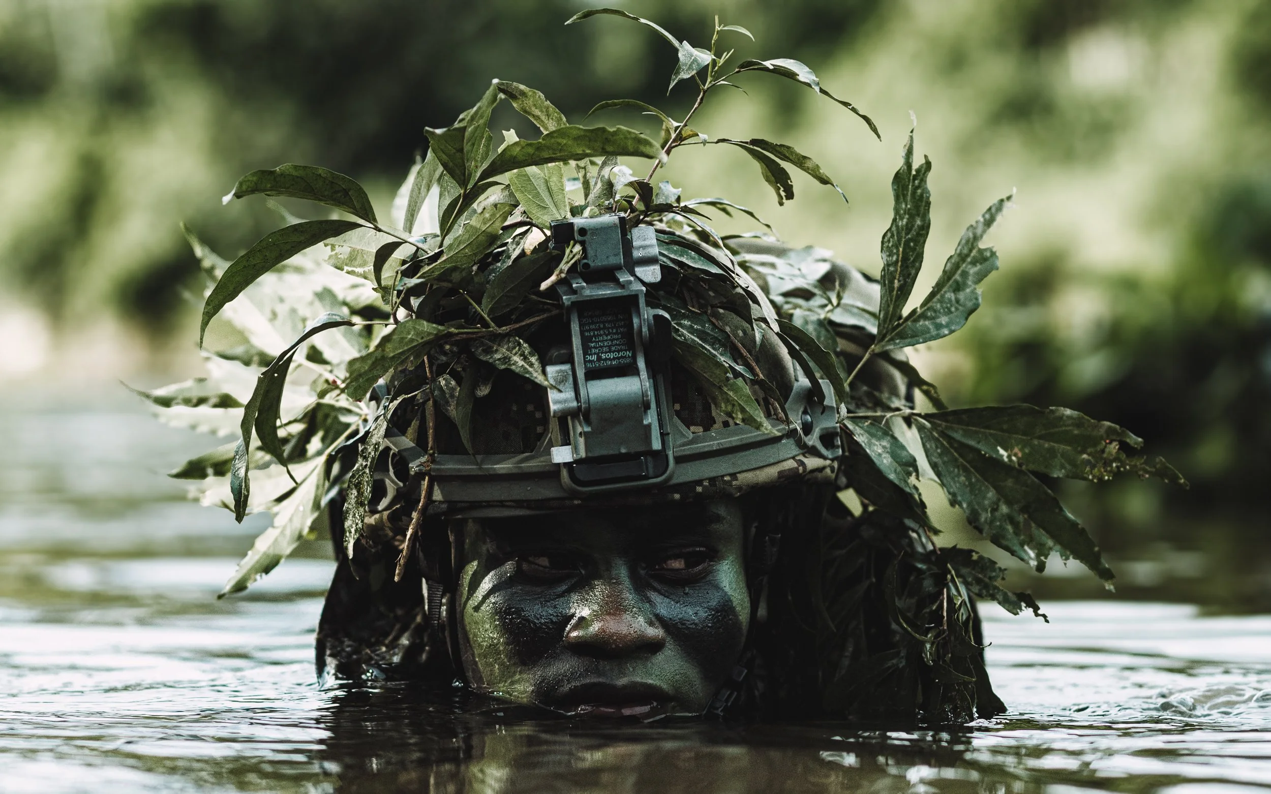 Camouflaged soldier submerged in a river
