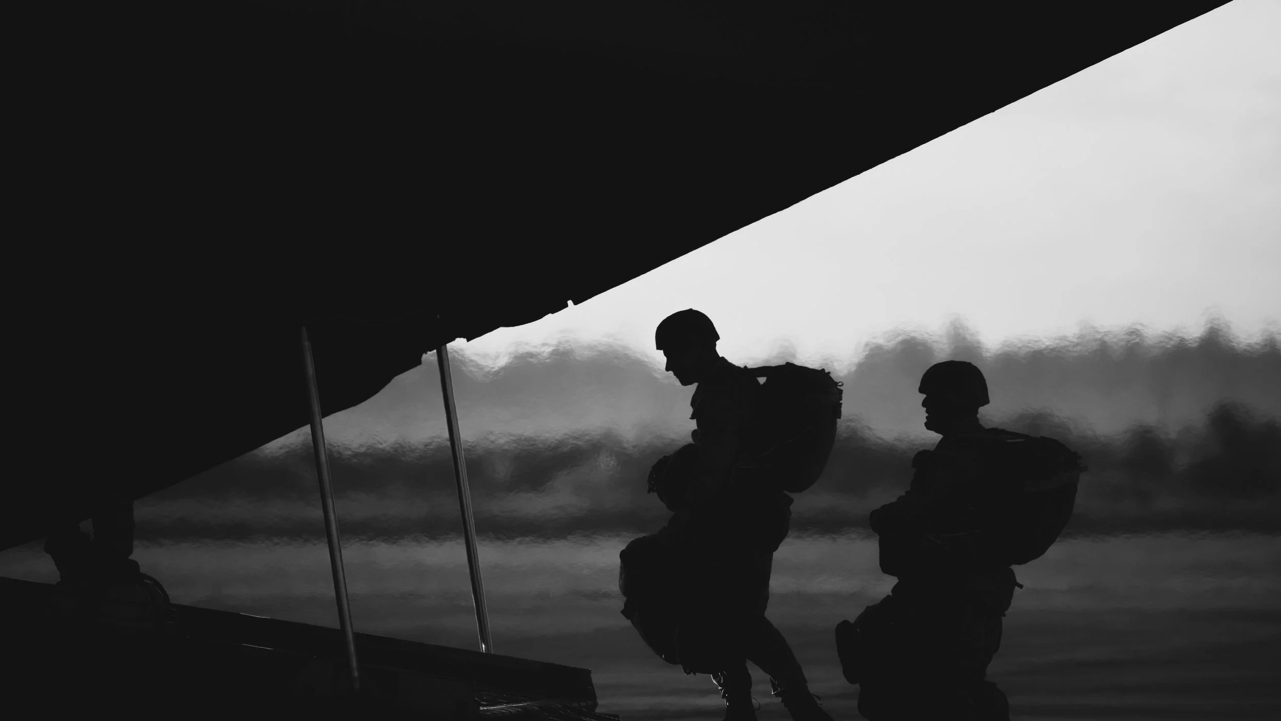 Two paratroopers in silhouette at the open door of an aircraft