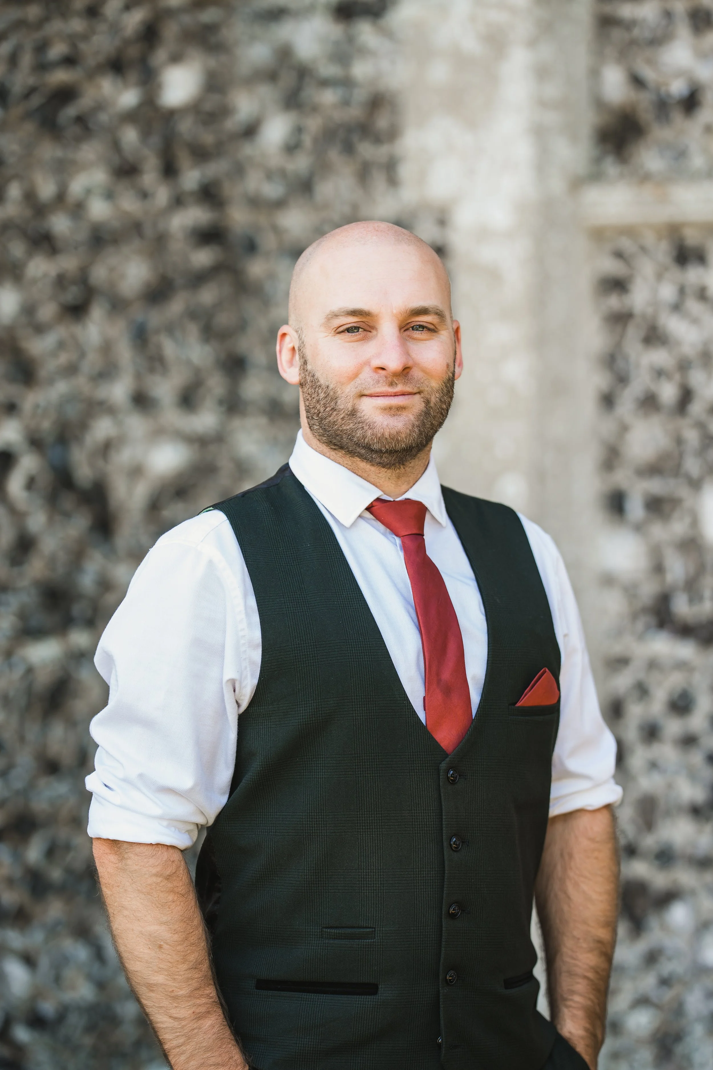 Lewis Horsley, wearing a white dress shirt, an orange tie, stood at The Elvetham wedding venue