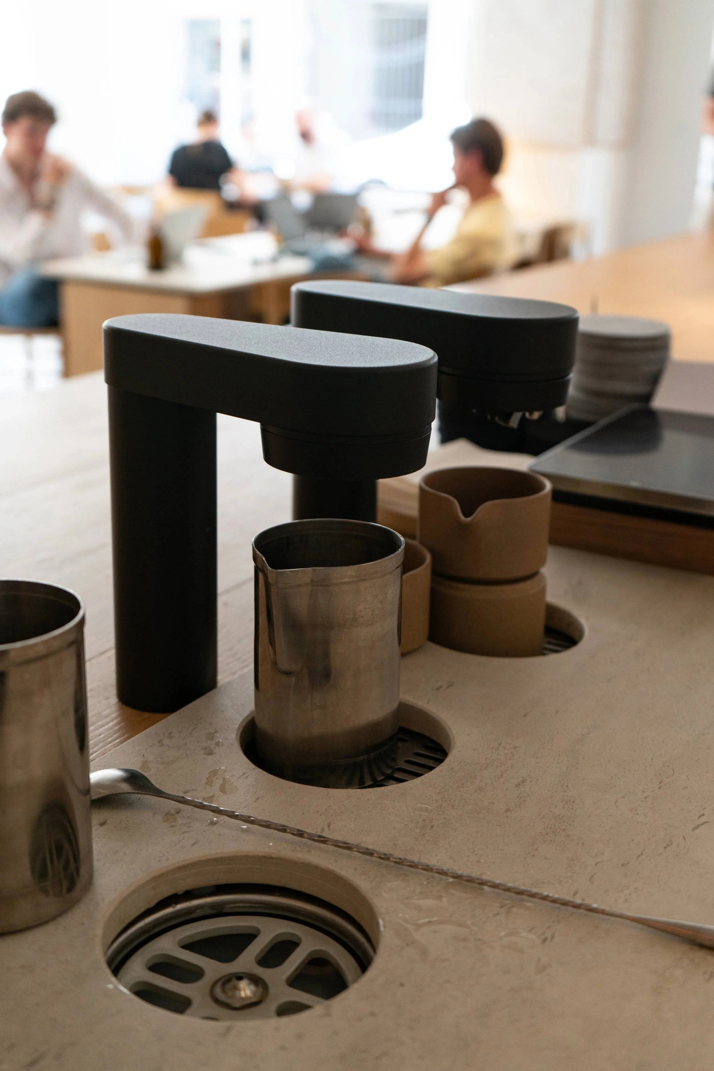 Close-up of Specter coffee taps with metal knock box built into café counter