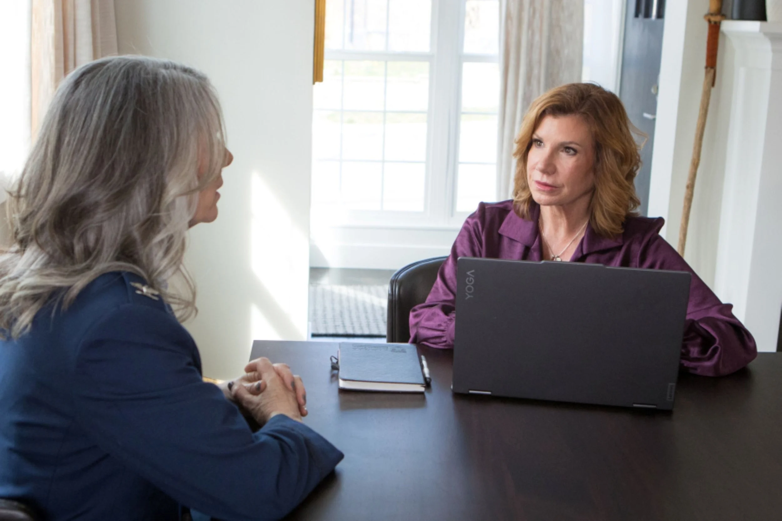 maureen farrell sitting at desk with laptop talking with women in military uniform