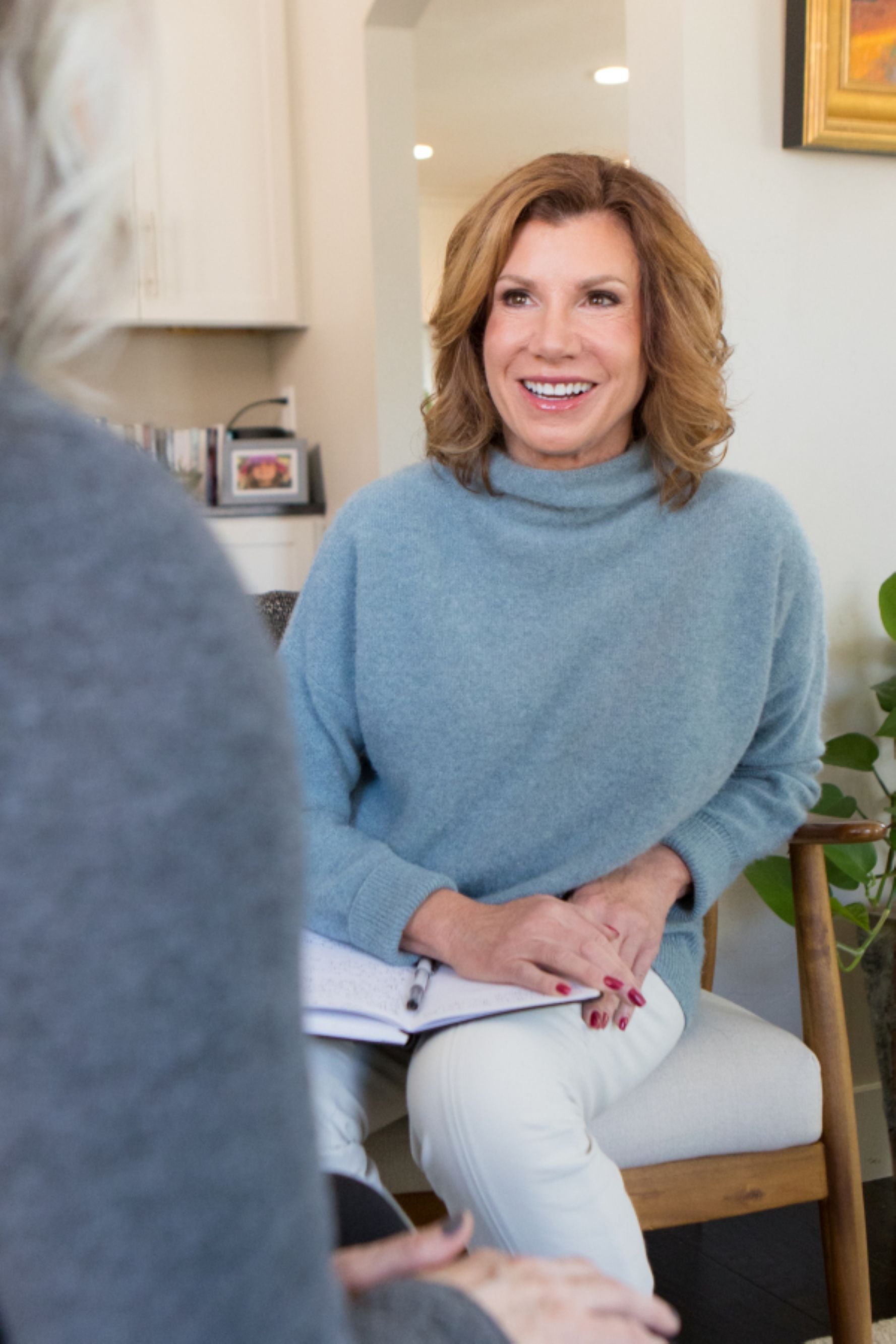 Maureen farrell in light blue sweater laughing while speaking with a client