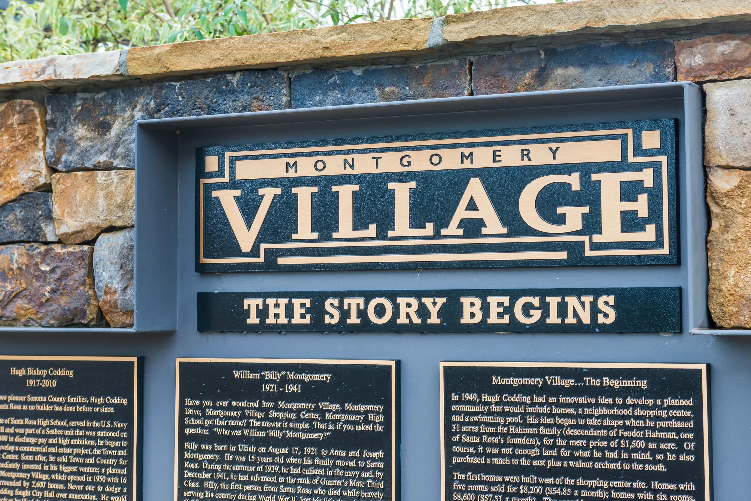 A stone sign board for Montgomery Village, with the title 'The story begins' and informational plaques about the history of Montgomery Village.