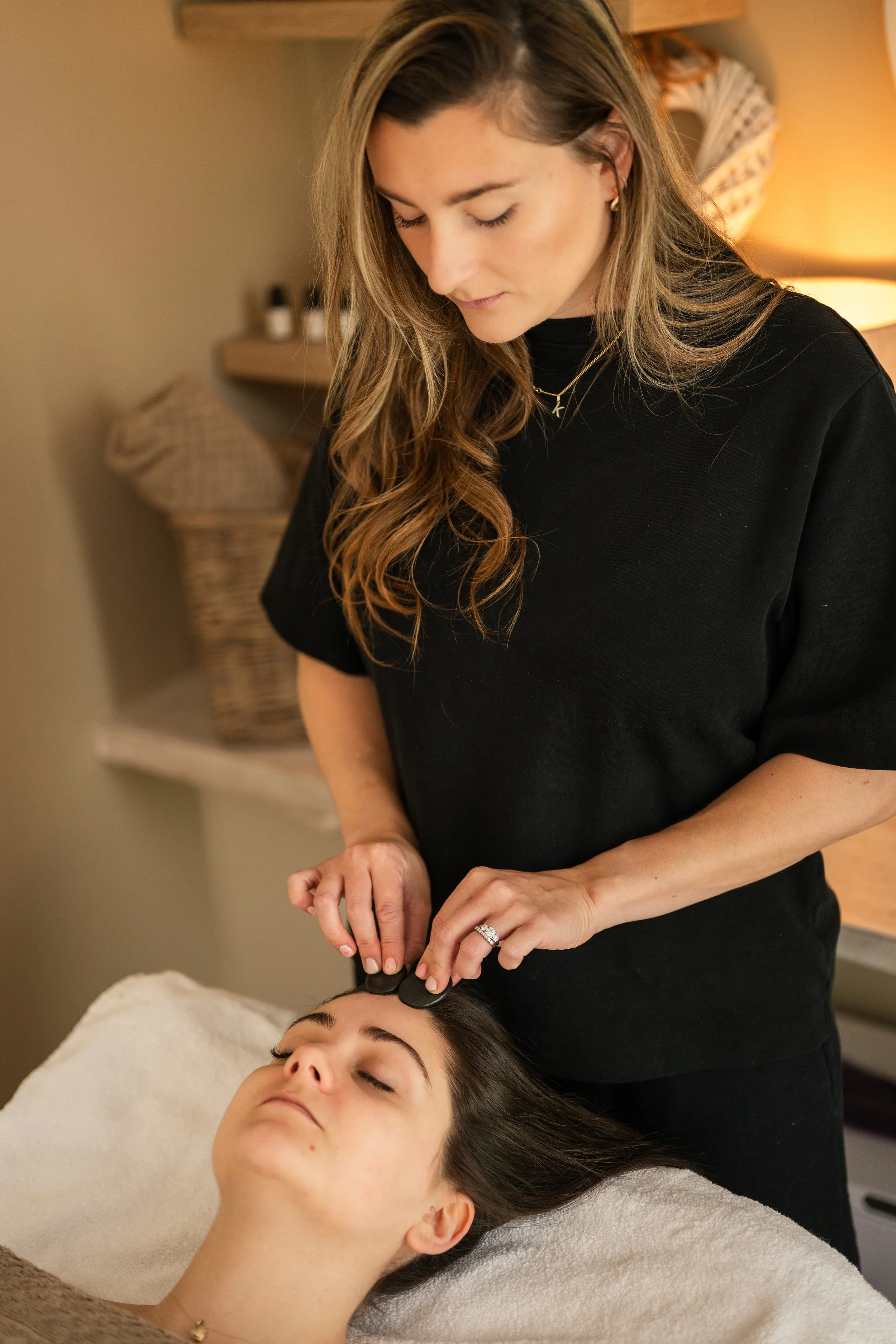 women standing behind client giving head massage during a brand photoshoot in worcester