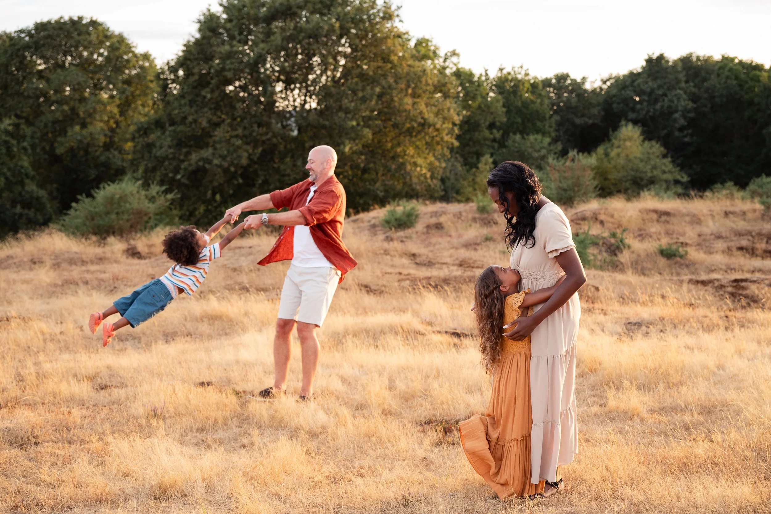 parents and two children playing together during a family outdoor sunset photoshoot in worcester, worcestershire, UK