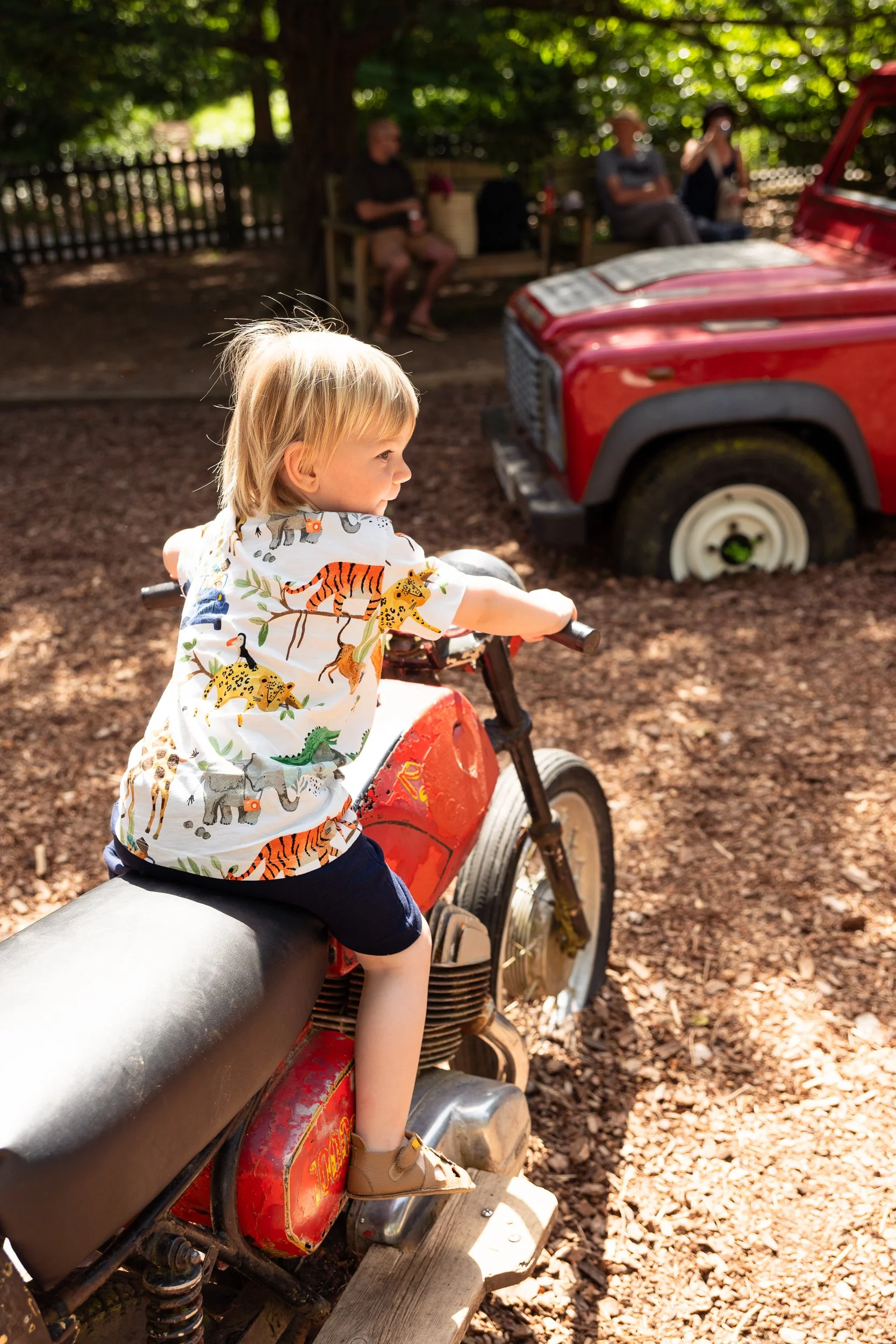 toddler sitting on motorbike in a playground at eastnor castle in Hereford. taken during a family photoshoot by Chloe Bower Photography the best worcester based family photographer