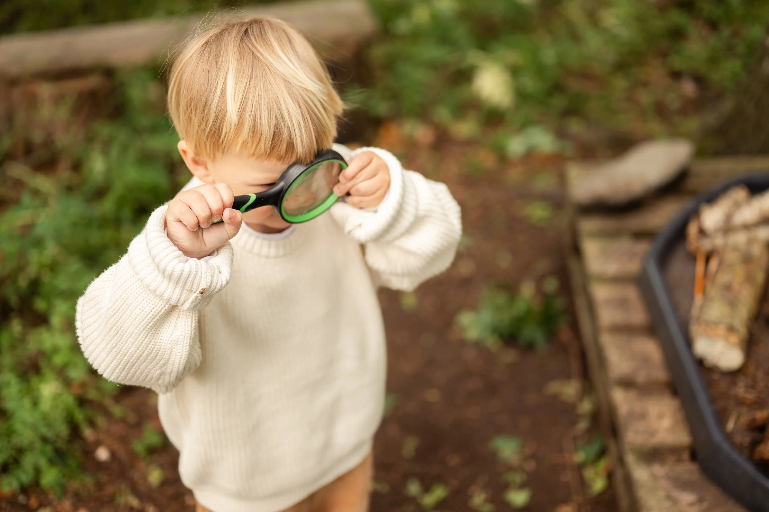 Toddler looking through a magnifying glass at a family photoshoot at Hoppity Poppits stay and play in Tewkesbury