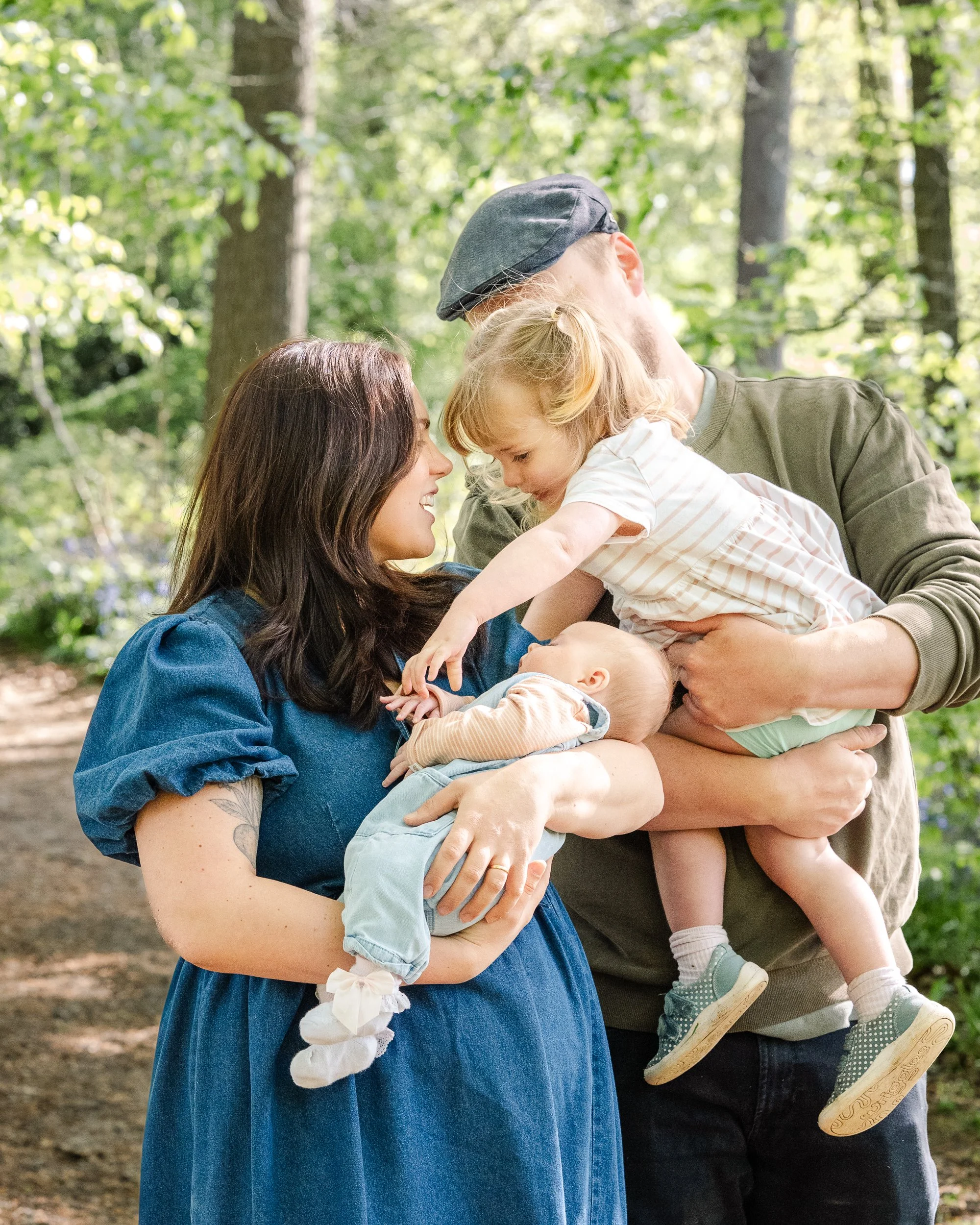 family cuddling in bluebell woodland in Droitwich during a family photoshoot done by Chloe Bower Photography a worcester based photographer.