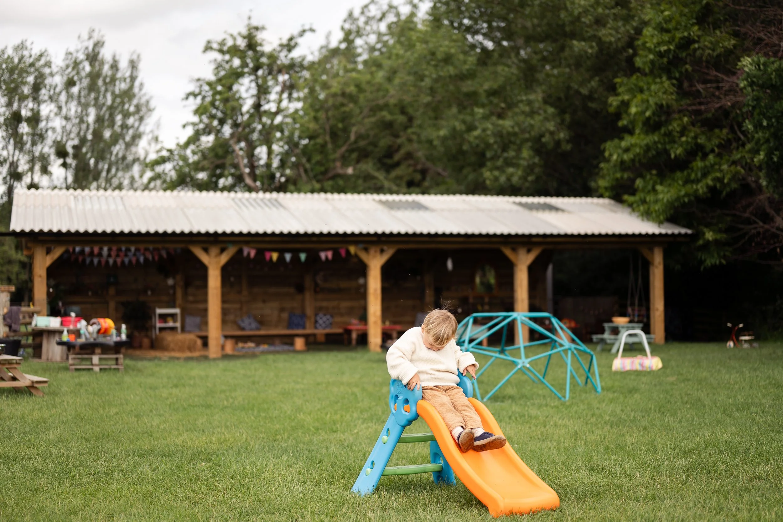 Toddler on slide in front of play area in Tewkesbury