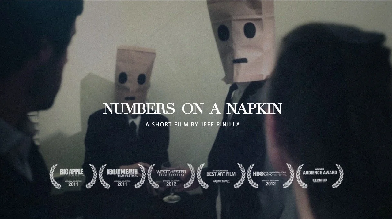 Film title screen for "Numbers on a Napkin" by Jeff Pinilla, featuring three people with paper bag masks over their faces, in a dark setting with laurels indicating film festival selections and awards.