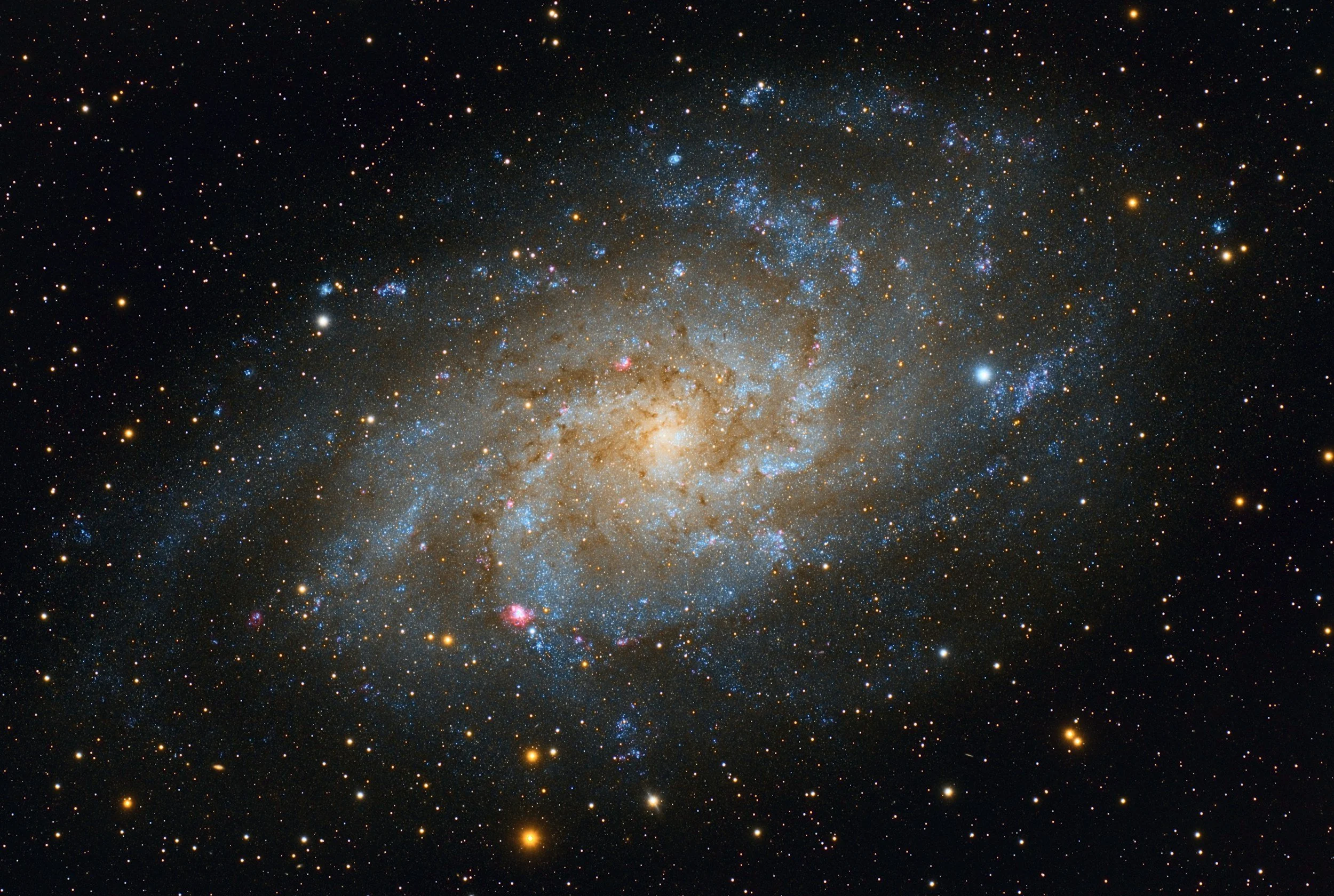 A detailed image of a galaxy with dense clusters of stars, dust, and cosmic clouds, displaying bright, colorful regions against the dark background of space.