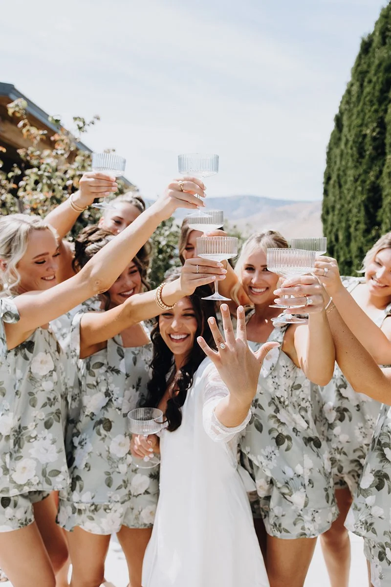 A group of women in floral pajamas celebrating with champagne glasses outdoors.