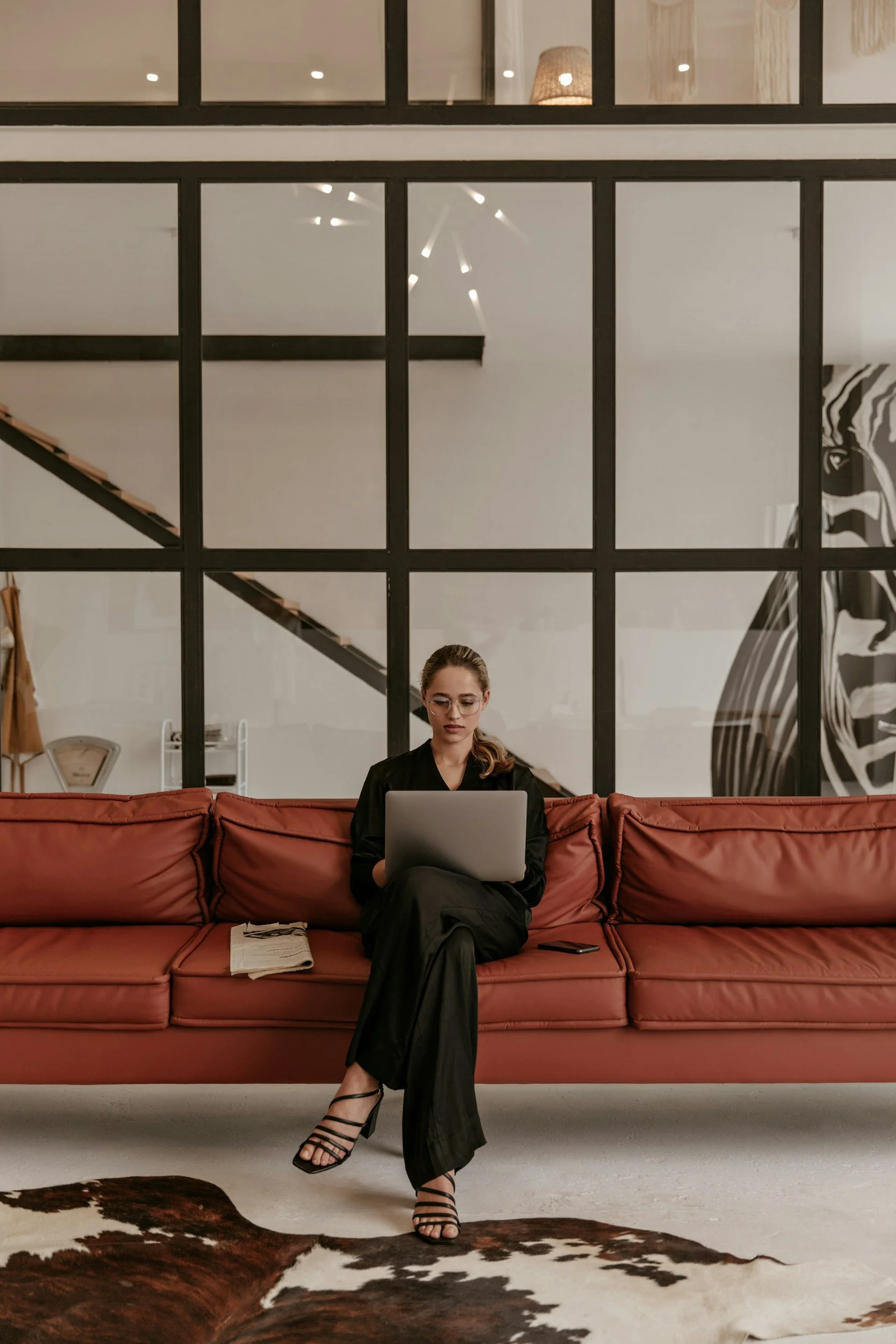 Woman working remotely on a laptop while sitting on a couch, representing virtual executive assistant services.
