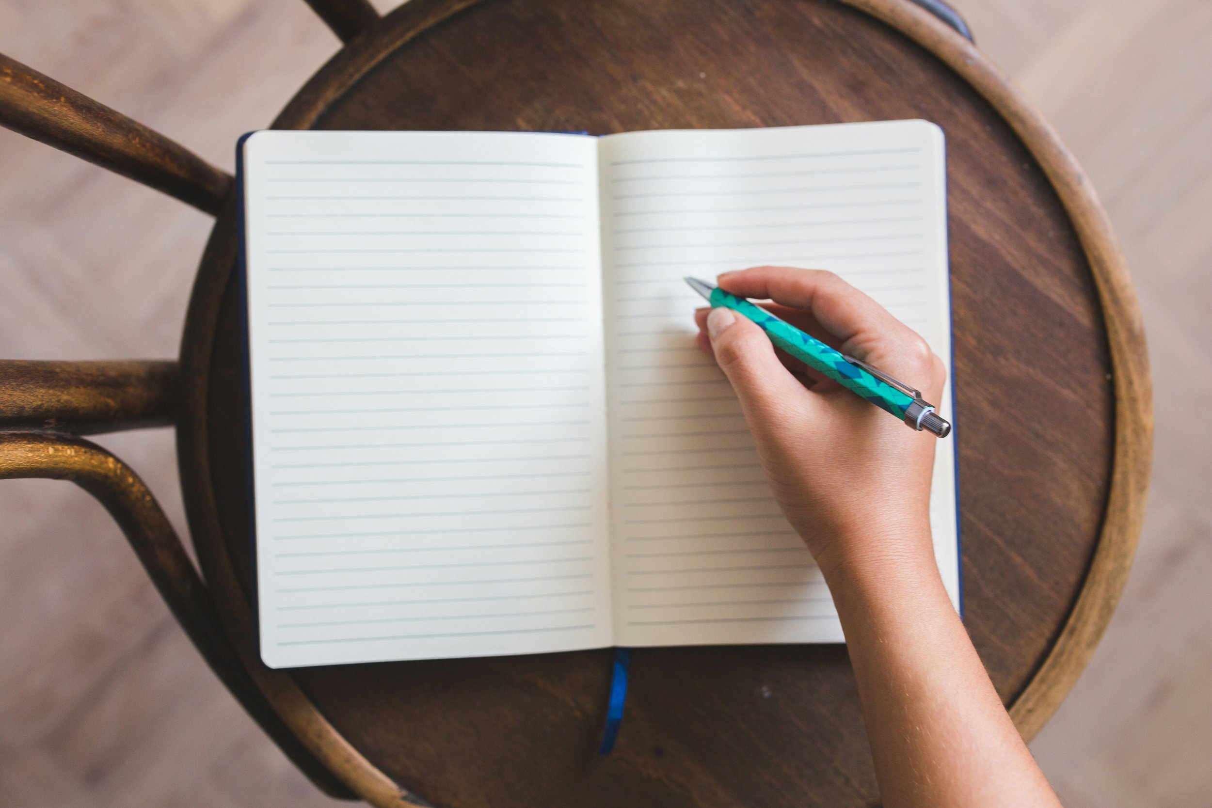 Person writing in an open notebook, representing reflection and journaling in therapy