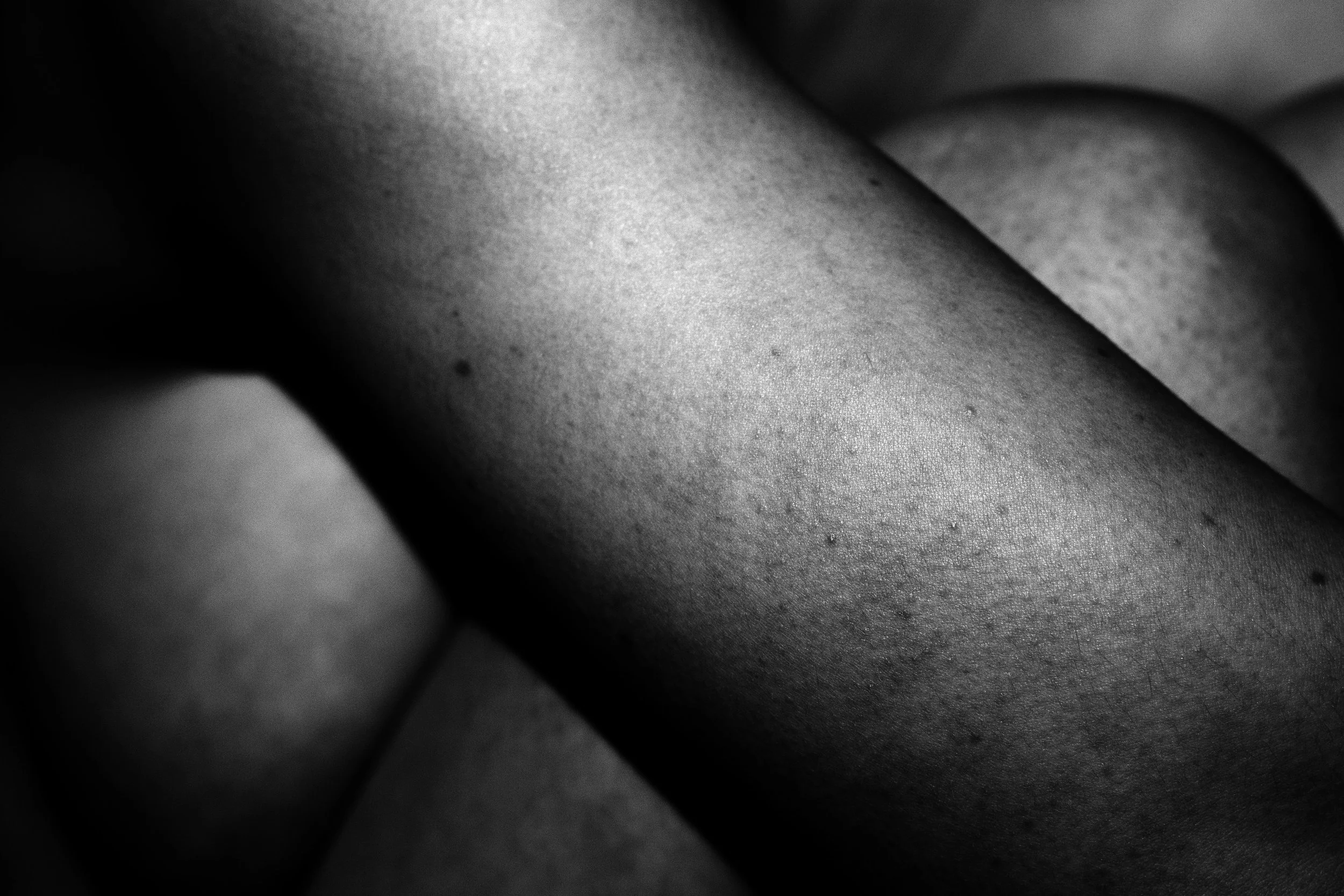 Close-up black-and-white photograph of human skin with smooth texture and subtle shadows.
