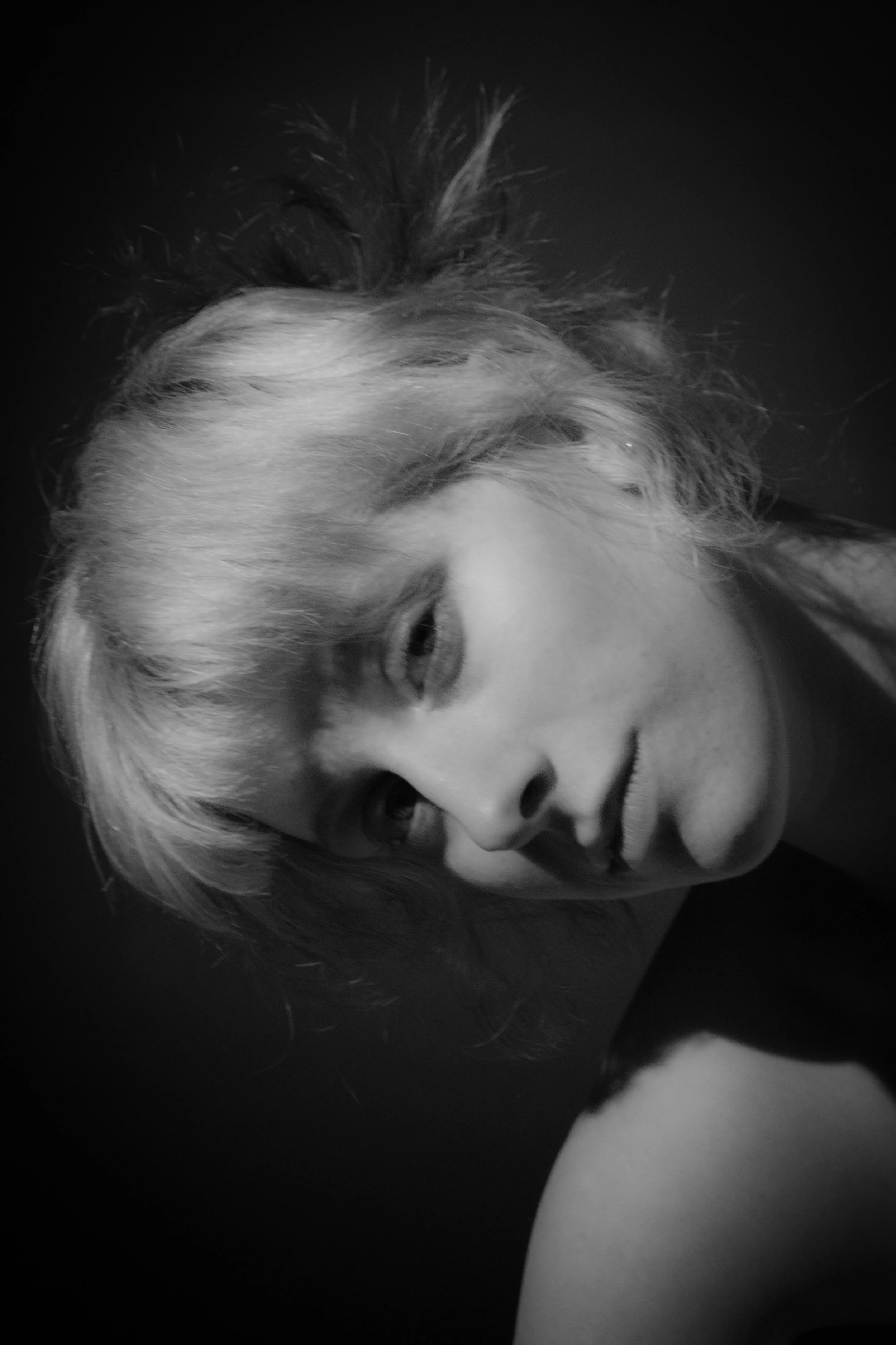 A black-and-white close-up photograph of a smiling woman with light-colored hair styled in a loose, curly updo.