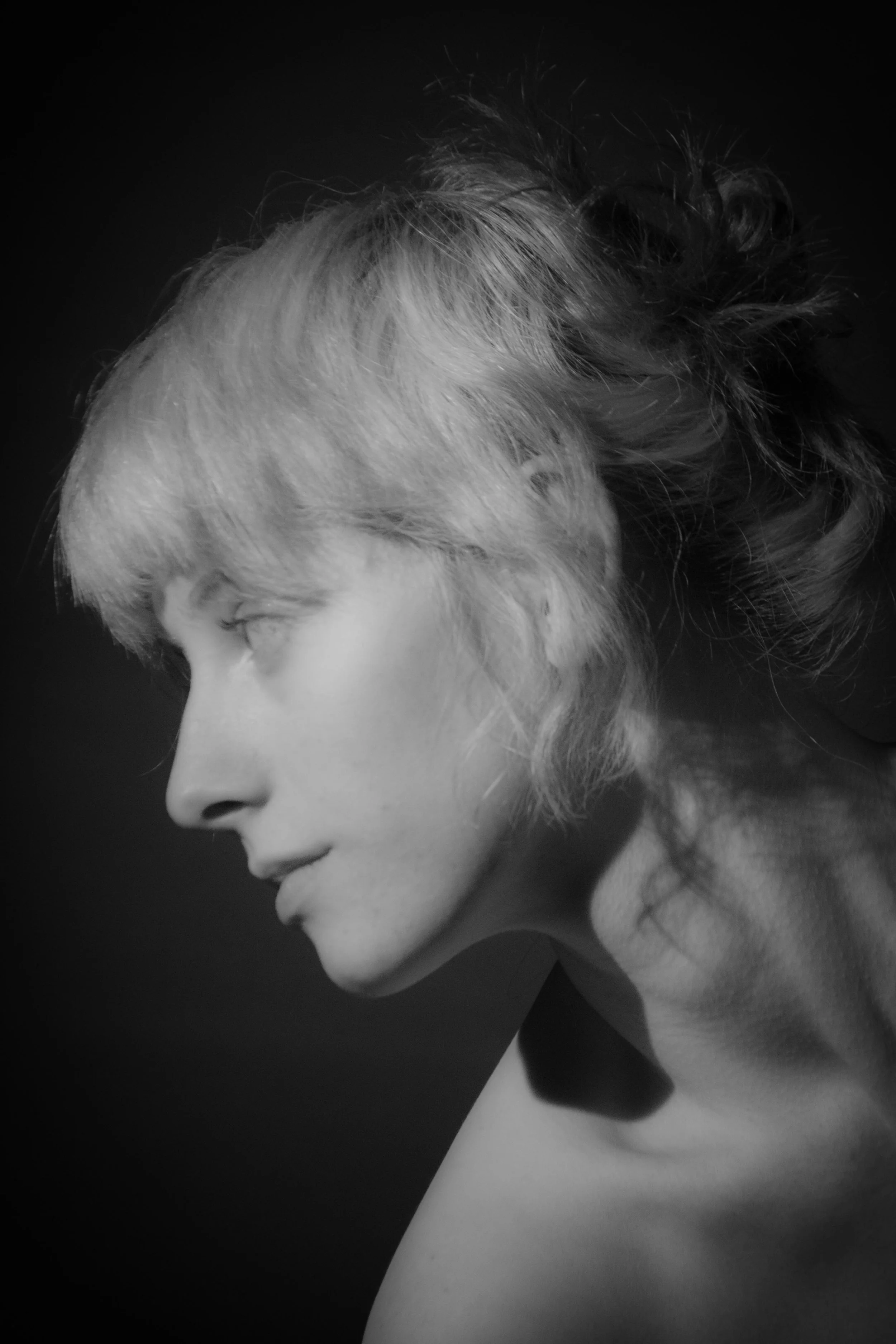 Black and white portrait of a woman with short, platinum blonde hair, eyes closed, and head tilted downward.
