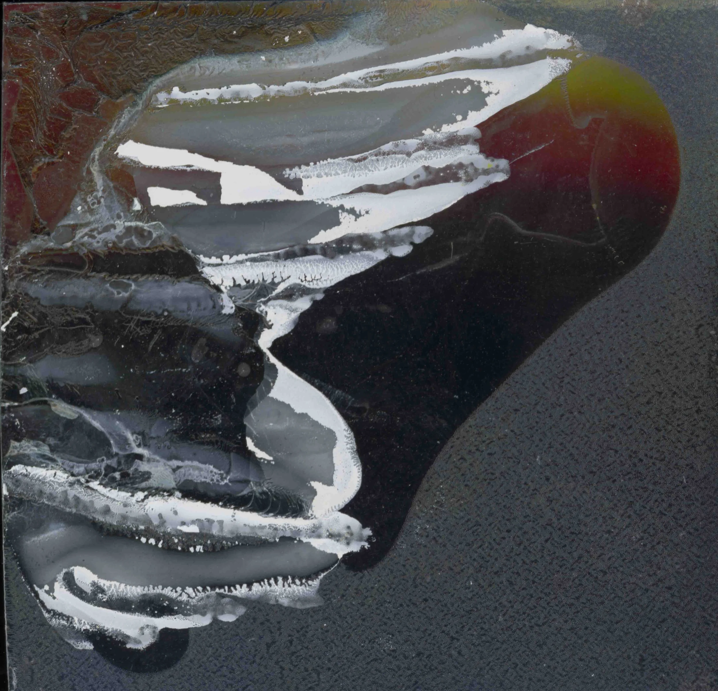 Close-up of black asphalt with irregular white streaks and patches that appear to be paint or chalk markings.