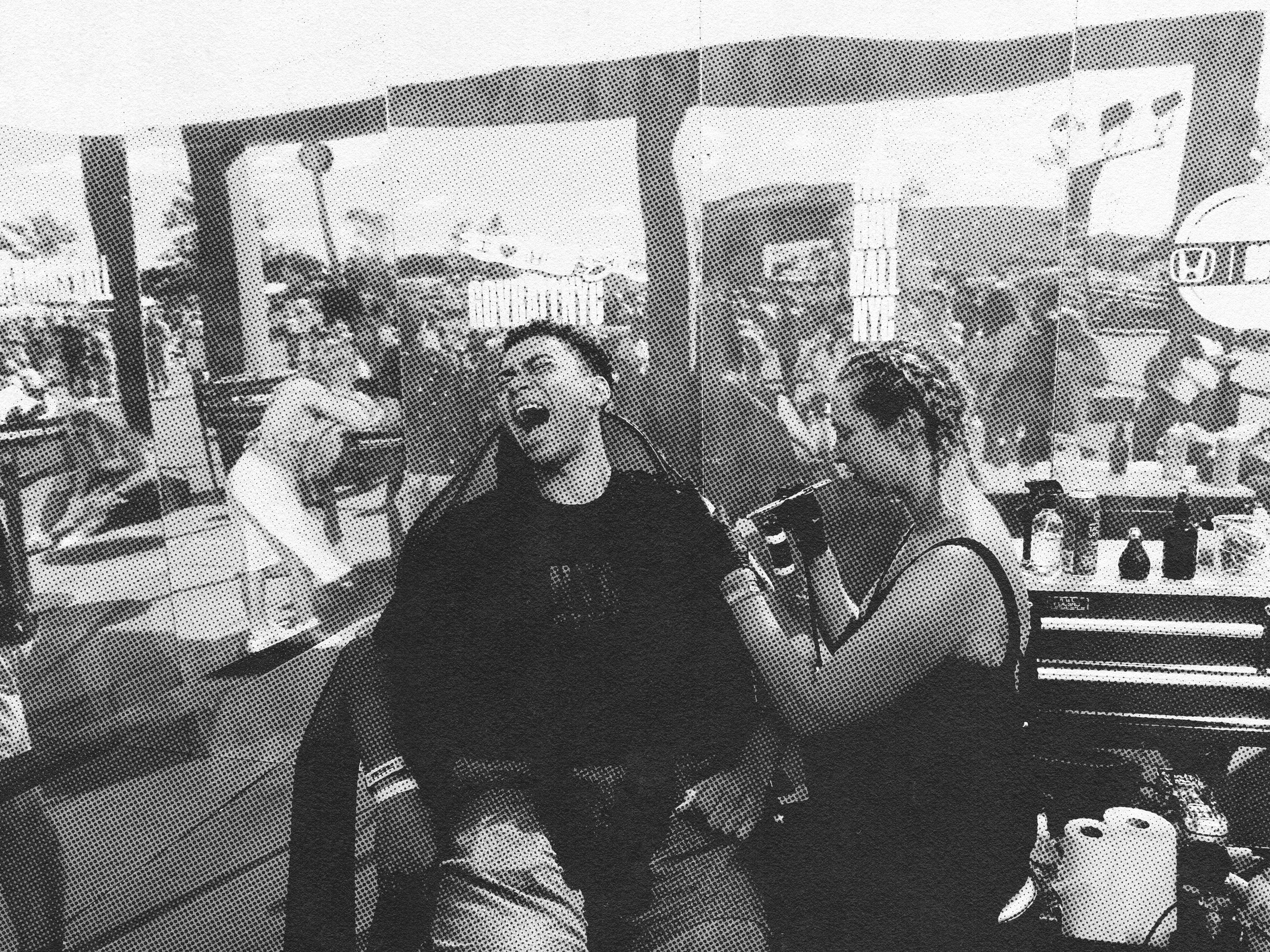 A temporary airbrush tattoo being done at a busy fair or festival, with booths and tents visible in the background. They are smiling and appear to be having fun.