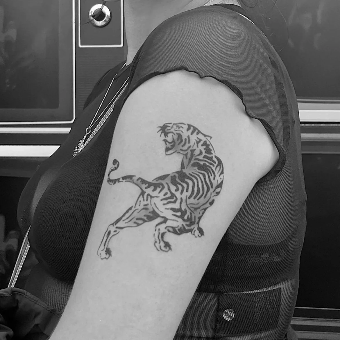 Black and white photo of a person's upper arm with a temporary tiger tattoo.
