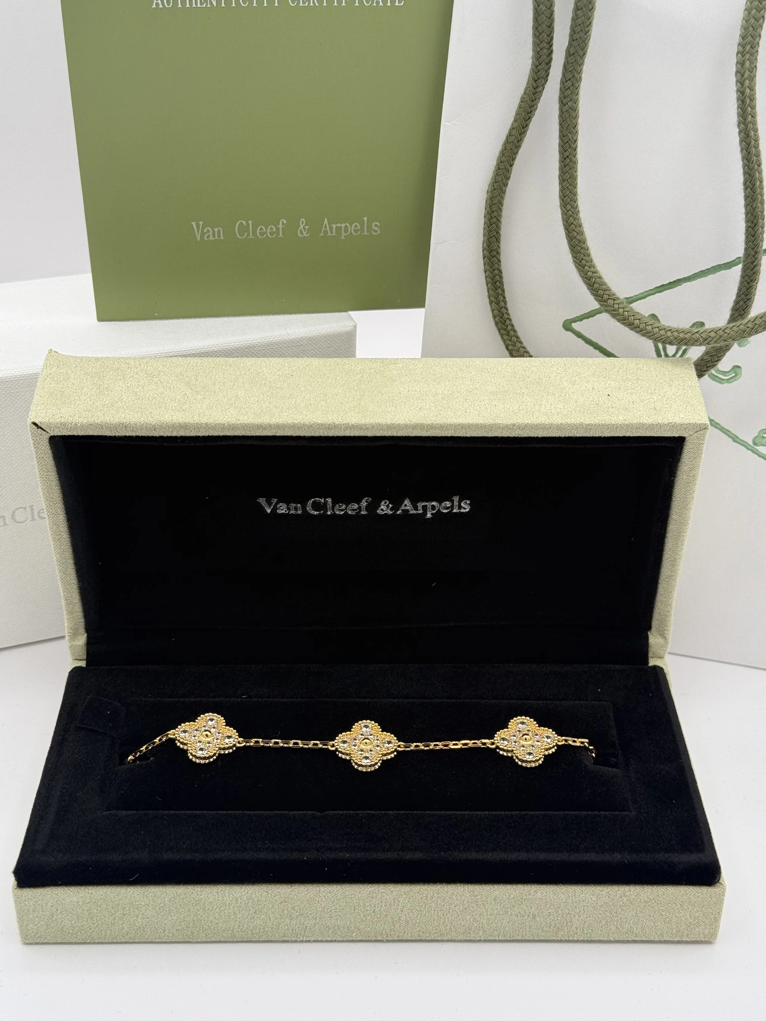 A gold bracelet with floral designs and small diamonds, displayed in an open black velvet jewelry box.