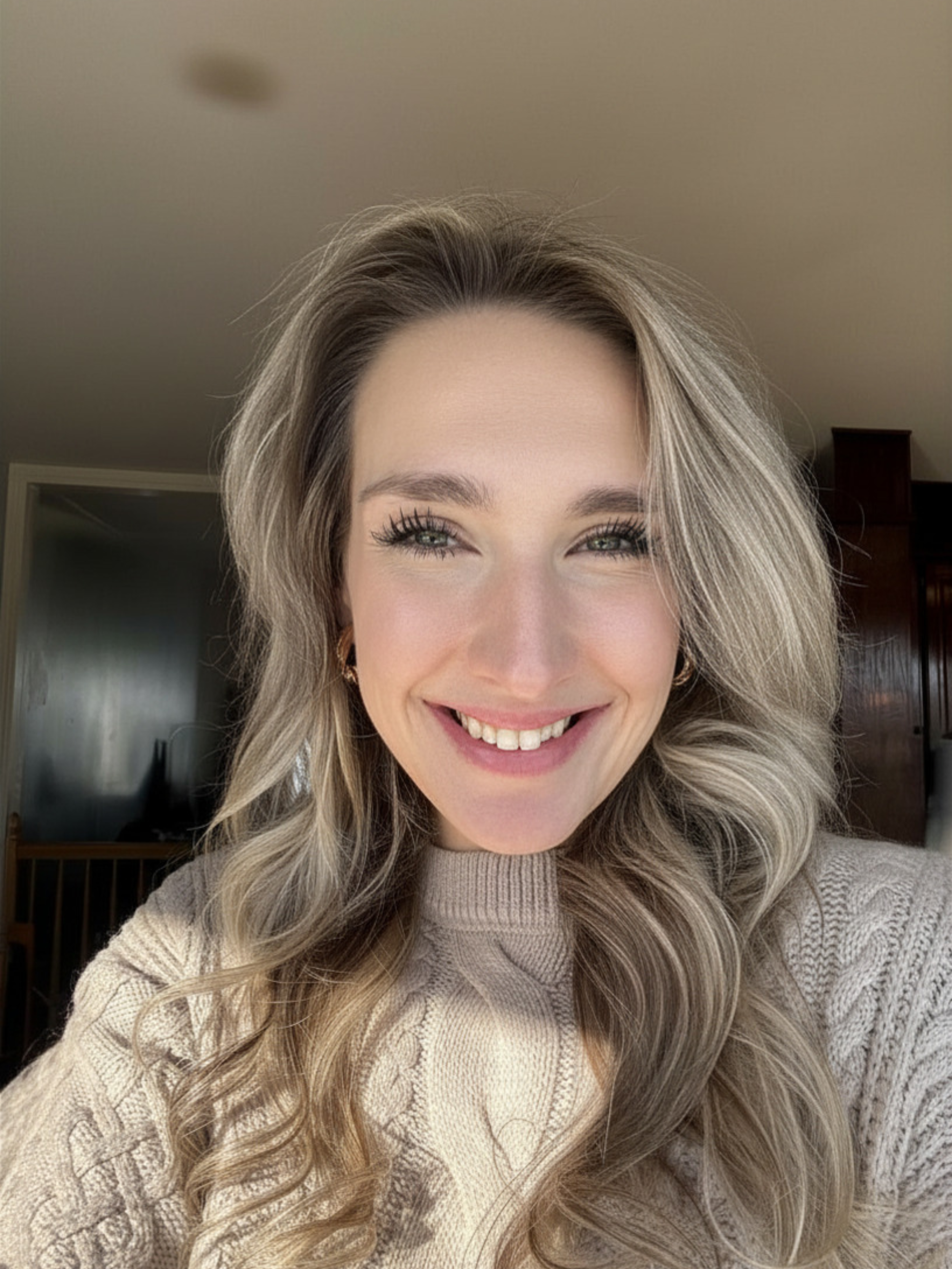 A woman with long, wavy blonde hair and bright eyes smiling at the camera.