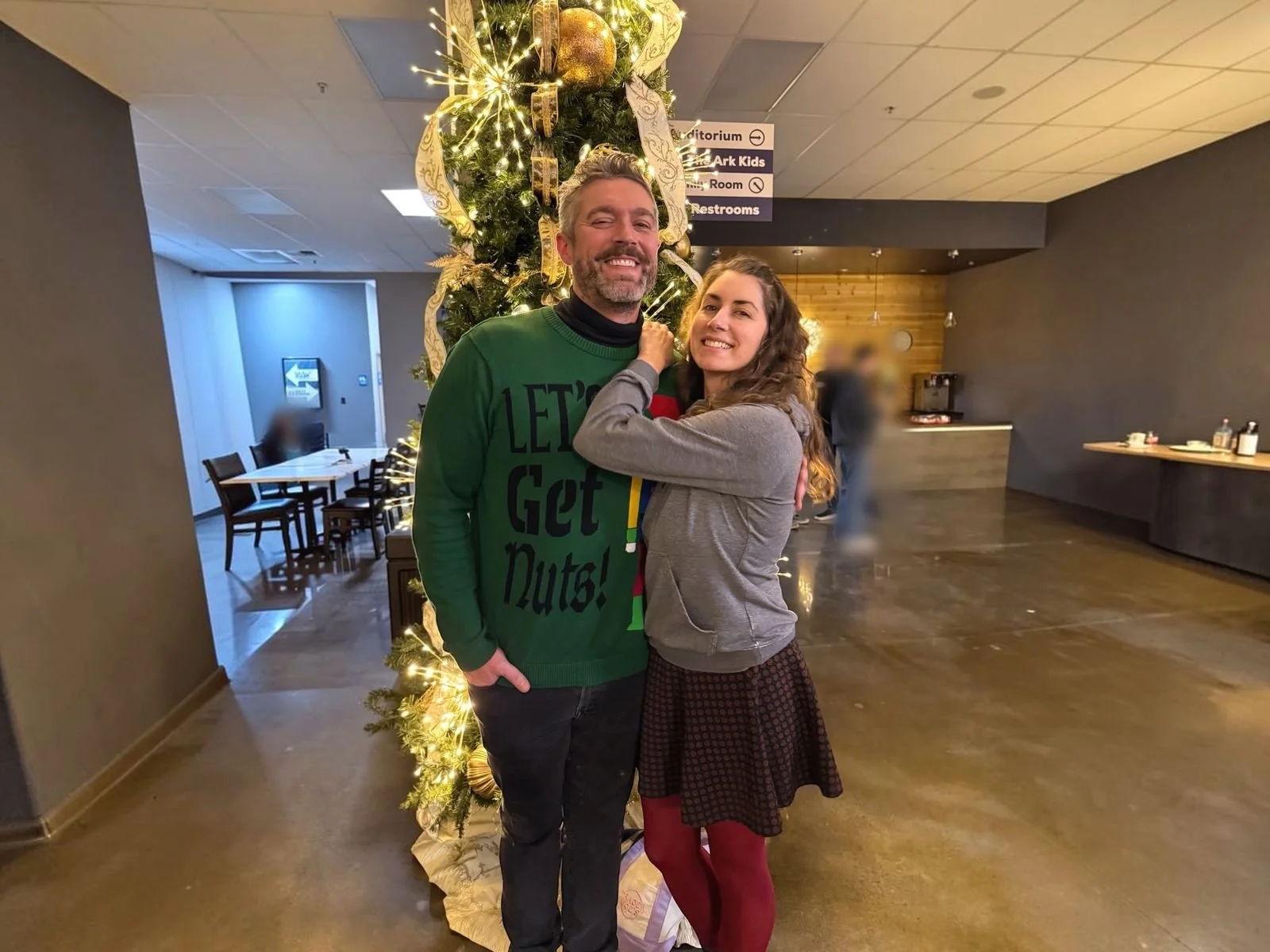 Adam Young and Natalie of Local Law Marketing sharing a laugh beside a Christmas tree