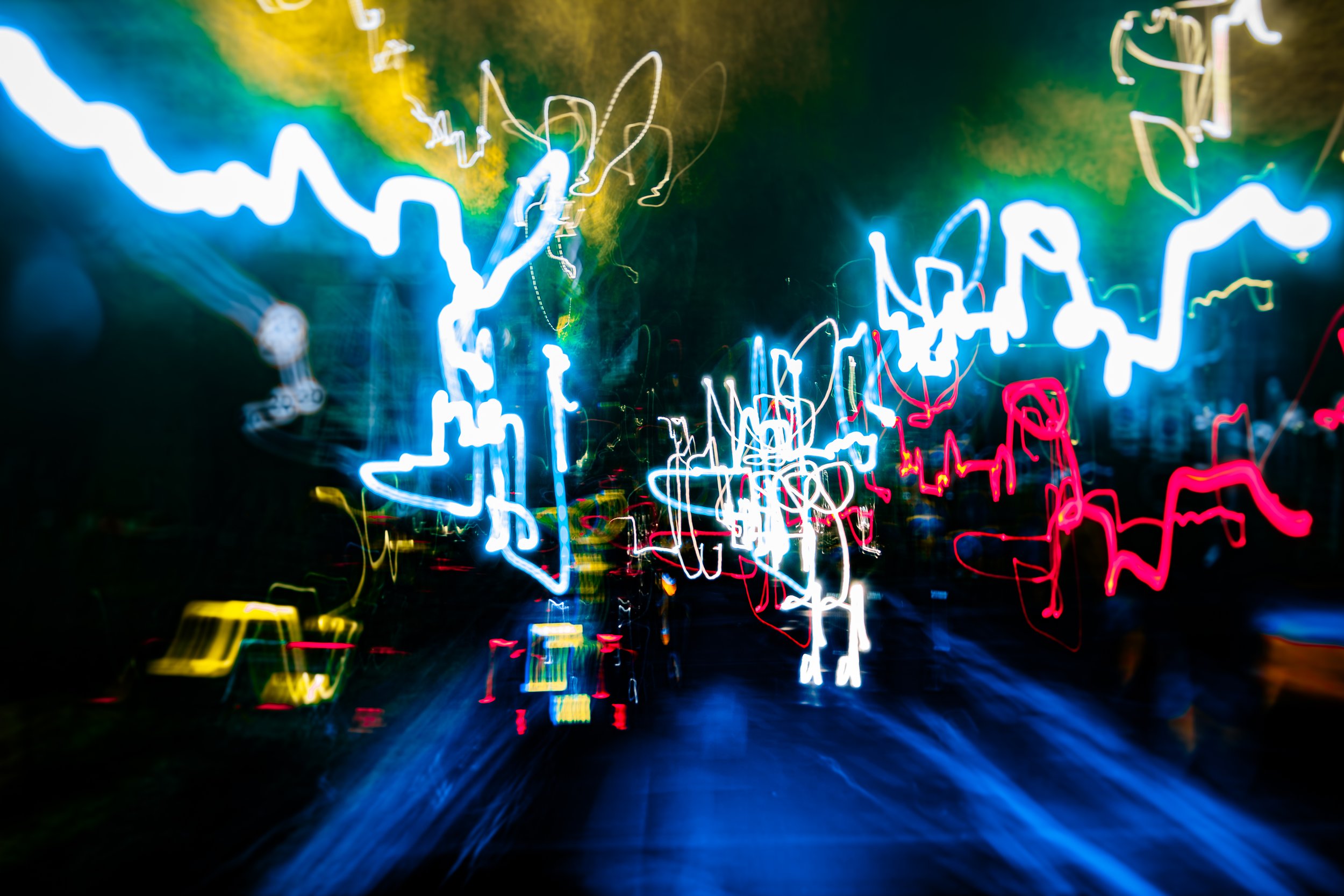 A long exposure photograph of a city street at night showing colorful lights and streaks of light from moving vehicles.