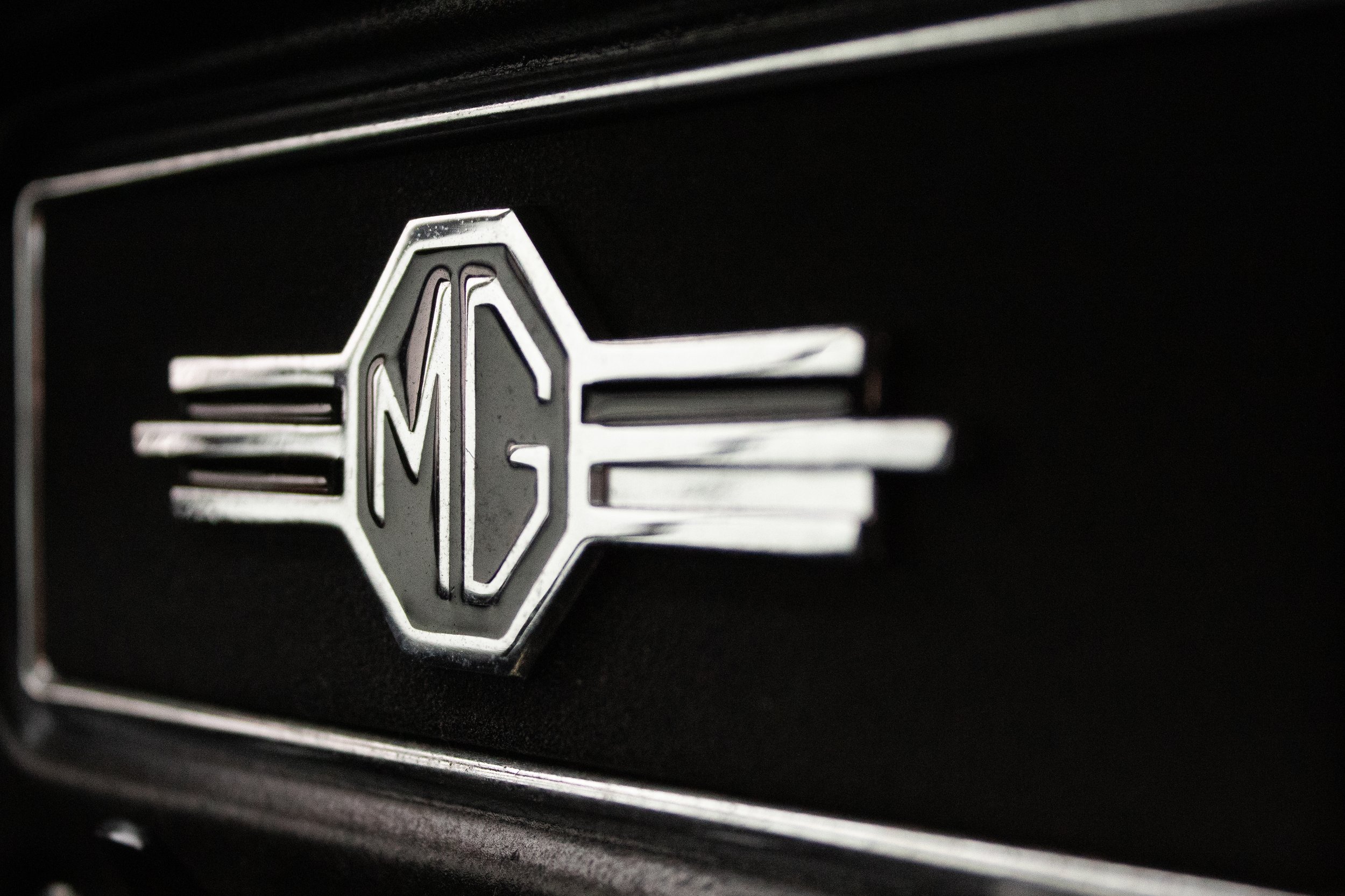 Close-up of a silver emblem with a circular center and wings extending on each side, mounted on a black surface.