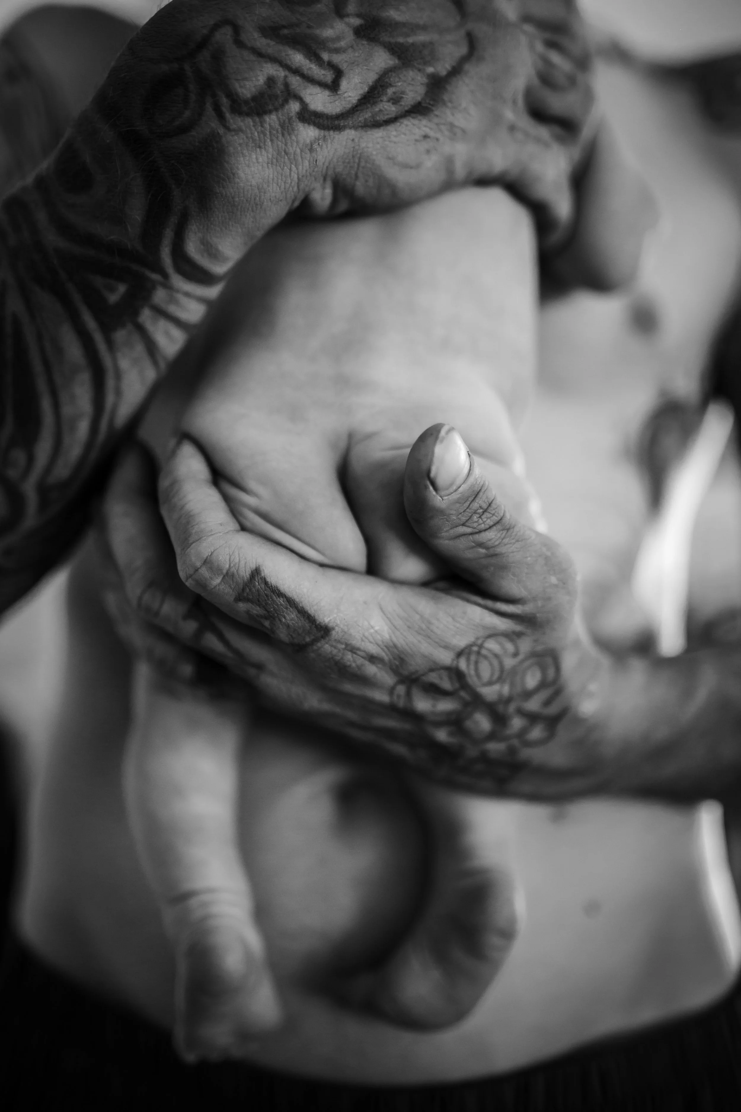 Close-up of a person's tattooed hand gripping another person's arm in black and white.