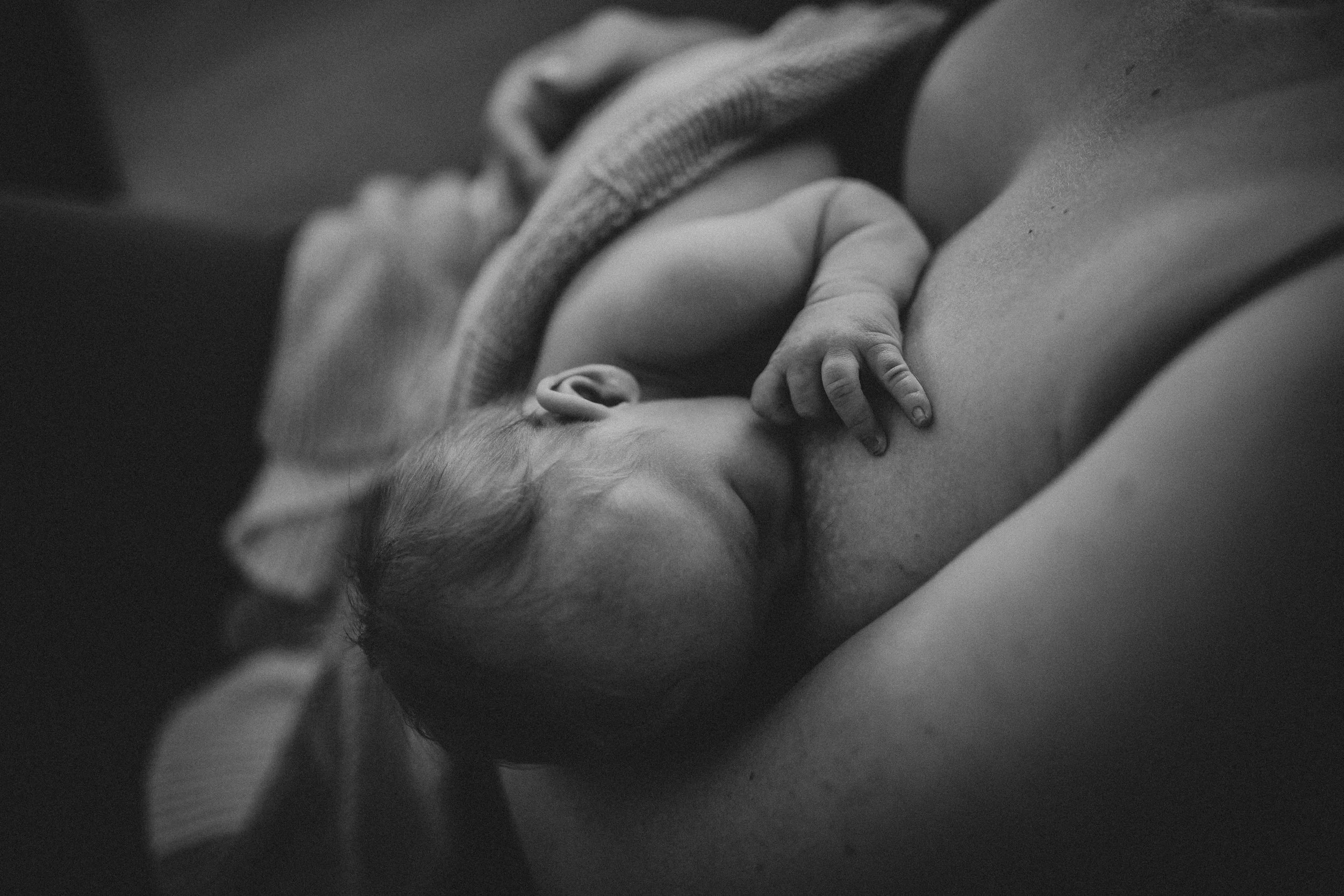 A black and white photo of a person lying down, with a hand touching their neck, focusing on their face and upper body.