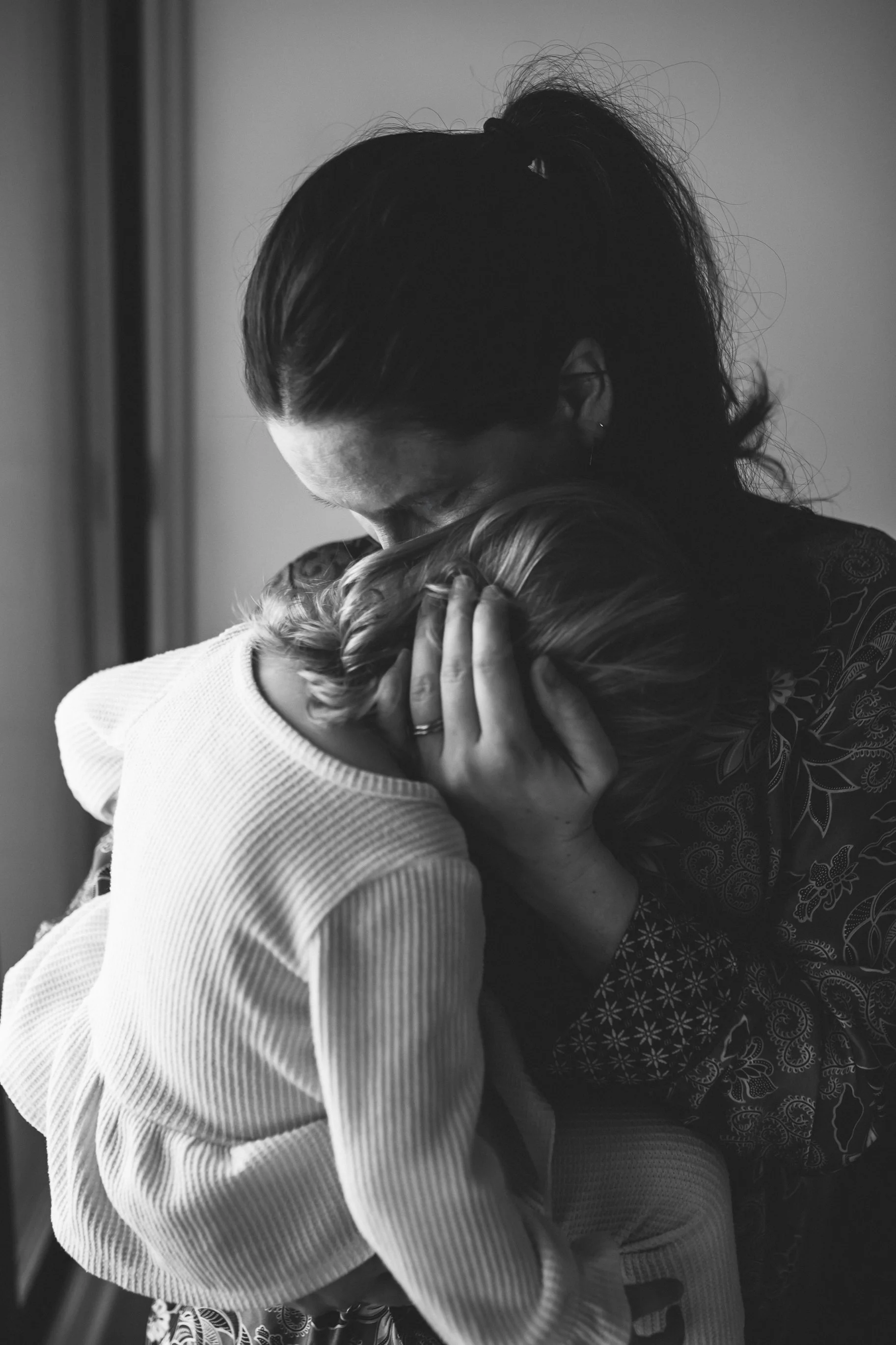 A black and white photo of two women hugging, one with dark hair and the other with light hair, showing an emotional embrace.