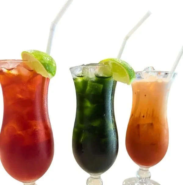 Three colorful cocktails with lime wedges and straws on a white background.
