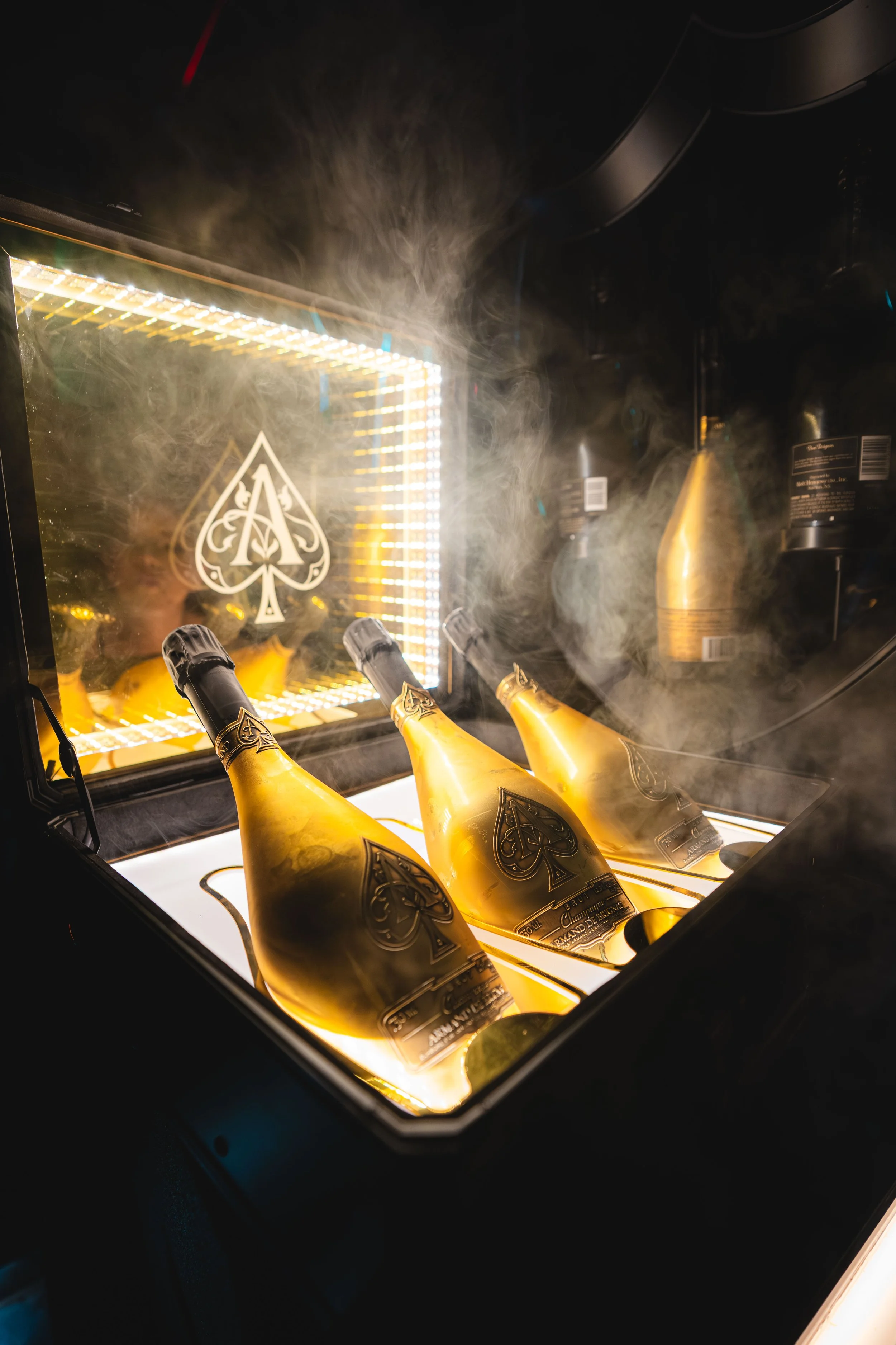 Golden champagne bottles inside a champagne cooler with a glowing illuminated background and a spade symbol on the cooler