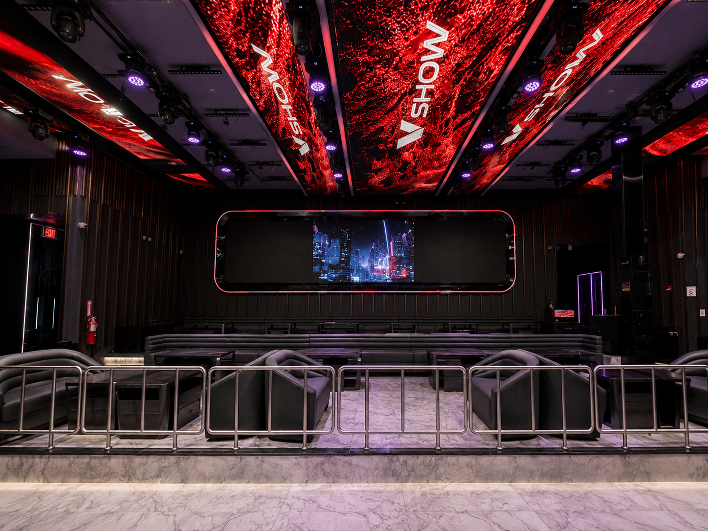 Empty modern lounge or event space with a large screen, black seating, and red LED lighting on the ceiling.